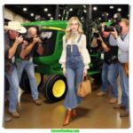 Oklahoma Dairy Show local woman and farmer, 20 something, blonde hair, dairy farmer chic fashion, arrives at the John Deere tractor and Holstein exhibit (1)