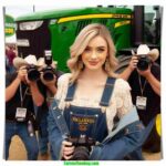 Oklahoma Dairy Show local woman and farmer, 20 something, blonde hair, dairy farmer chic fashion, arrives at the John Deere tractor and Holstein exhibit (6)